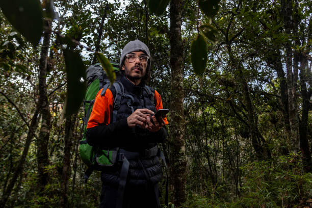 uomo in un viaggio avventuroso attraverso una foresta con foglie secche pavimento della colombia, accanto a lei uno zaino verde - journey footpath exercising effort foto e immagini stock