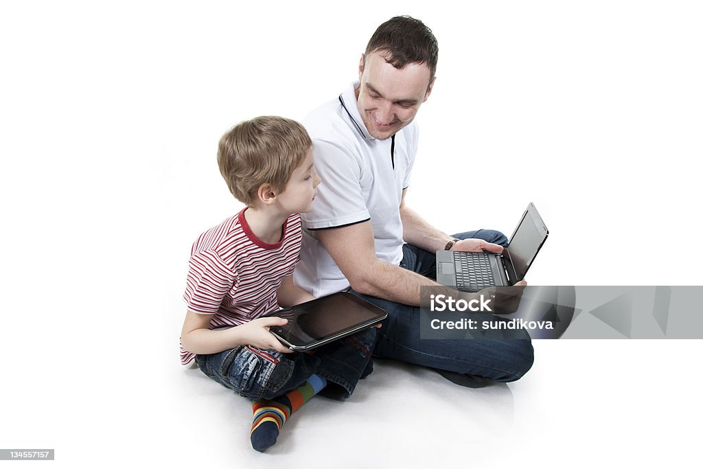 Father and son with the computer. Father and son sitting on a floor with the computer on white isolation Father Stock Photo