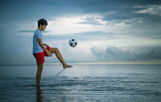 Teen juggling and practicing with a soccer ball at a beach in Miami