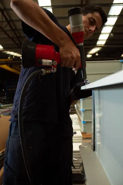 closeup of worker riveting with rivet gun building skylight.Close-up male hand holds a riveter and rivets aluminum profiles