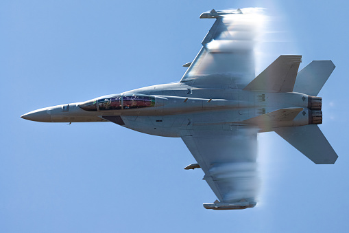 Very close view of a U.S. Navy EA-18G Growler in a high G maneuver, with afterburners on and condensation streaks at the wings