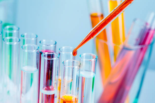 istock Laboratory test tubes with red and yellow liquids on light blue background 1345576938