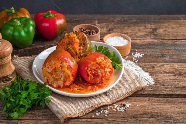 pimentão recheado com peru, arroz e legumes em um fundo de madeira marrom - stuffed stuffed pepper pepper bell pepper - fotografias e filmes do acervo