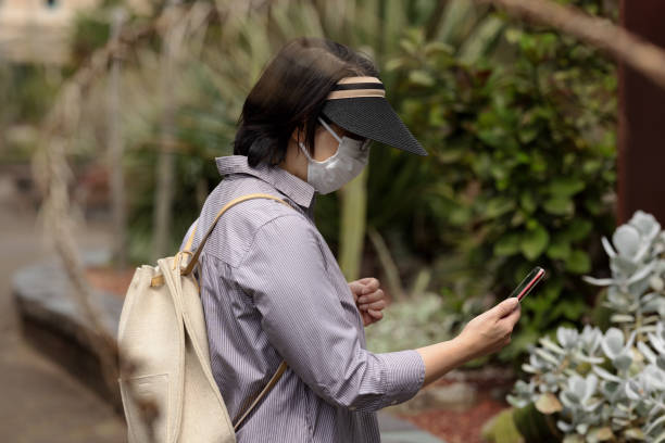 istock Woman with face mask using her phone 1345587376