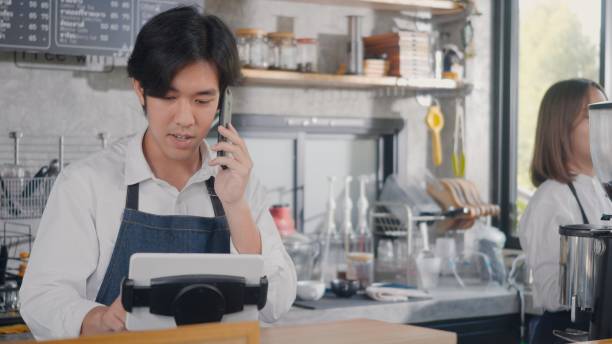 istock barista man coffee maker receive phone call and record pre order to computer in coffee cafe shop 1345590054