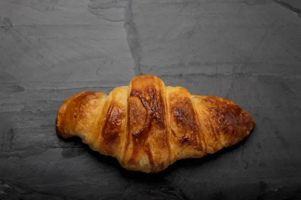 Homemade croissant on black slate background