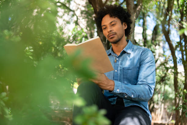 istock man reading book for leisure in the park 1345591110