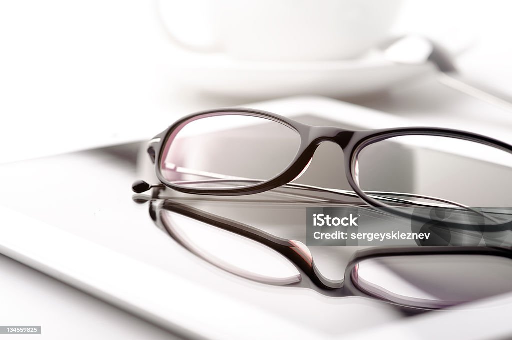 Tablet, coffee cup and glasses on a white table Still life with white tablet, coffee cup and glasses on a white table Business Stock Photo