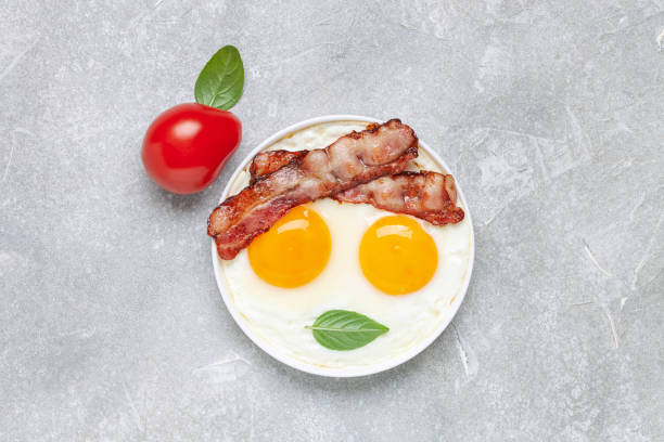istock English breakfast - eggs, bacon and basil leaves in a plate. Top view 1345602534
