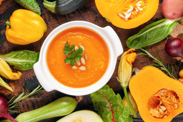 istock Pumpkin soup and various vegetables on a dark background. Top view. 1345602560