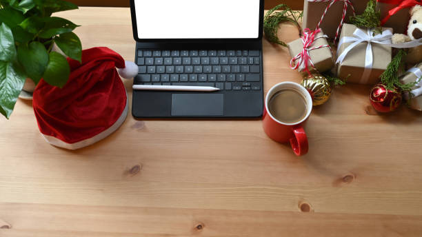 istock Digital tablet, Santa hat and Christmas gift boxes on wooden table. 1345607270