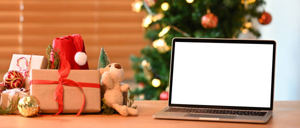 istock Mock up laptop computer and Christmas gift boxes on wooden table. 1345607294