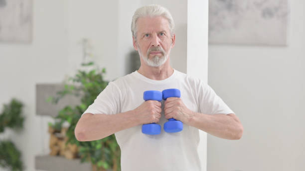 istock Old Man Working out with Dumbbells at Home 1345614021