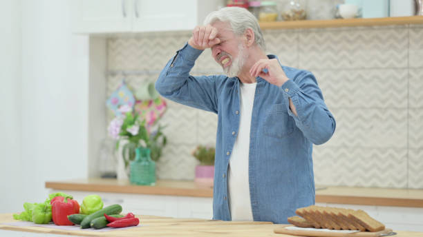 istock Frustrated Old Man with Headache Standing in Kitchen 1345614040