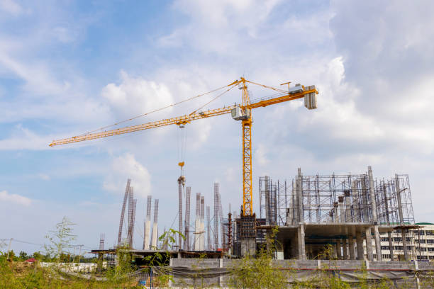 istock Working at height equipment with bucket liquid concrete container. Construction worker working on a high building. Crane lifting Cement mixer machine to  building. Crane lift concrete mixer container 1345615157