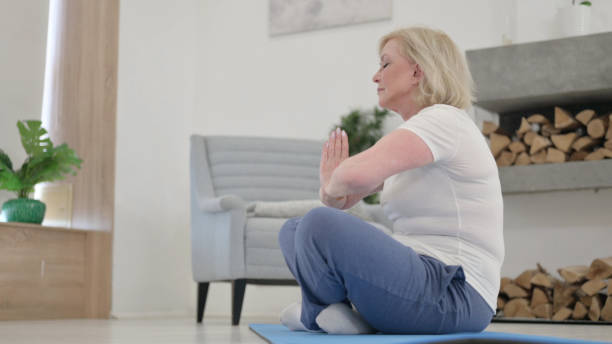 istock Relaxing Old Woman Meditating at Home 1345616093