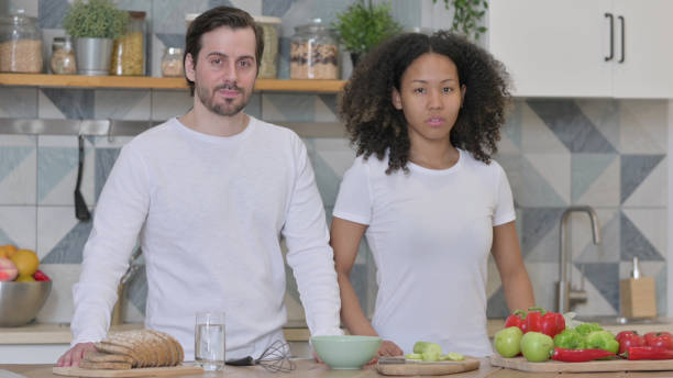 istock Mixed Race Couple Looking at Camera in Kitchen 1345617769