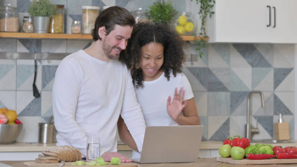 istock Mixed Race Couple Doing Video Call on Laptop in Kitchen 1345617865