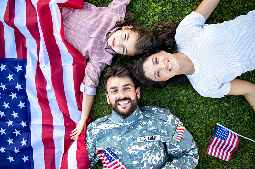 Top view of military family lying on the grass enjoying time together with soldier coming home.