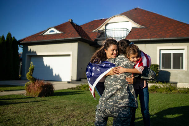 żołnierz w mundurze wracający do domu i jego urocza rodzina z amerykańską flagą biegnącą w ramiona z okazji ponownego spotkania. - patriotism child american culture flag zdjęcia i obrazy z banku zdjęć