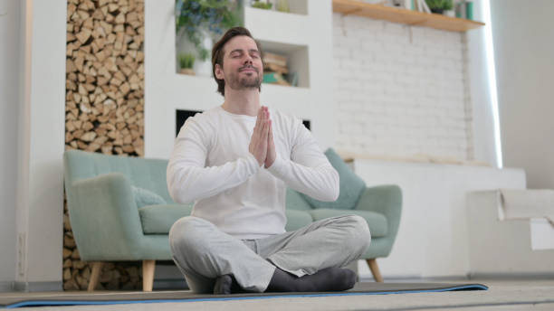 istock Young Man Meditating on Excercise Mat at home 1345618041