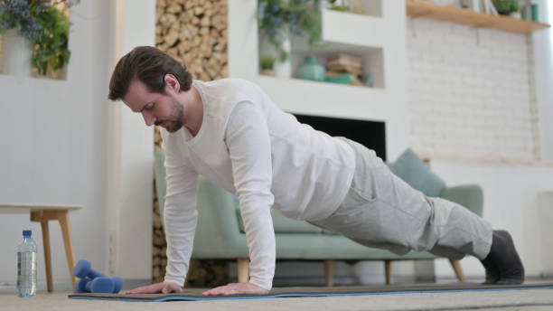 joven haciendo flexiones en la colchoneta de ejercicio en casa - 24187 fotografías e imágenes de stock