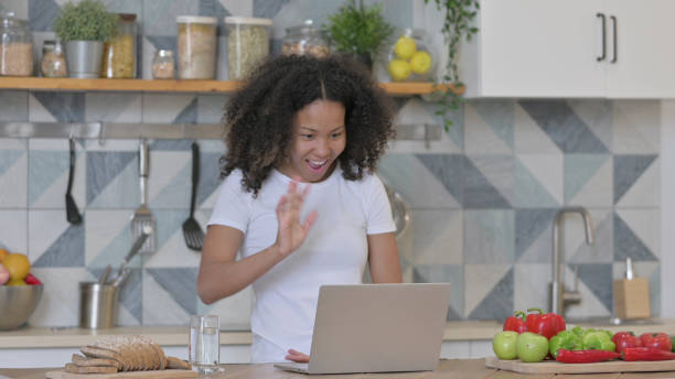 istock Young African Woman doing Video Call on Laptop in Kitchen 1345619286