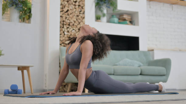 istock Young African Woman doing Yoga on Excercise Mat at home 1345619321