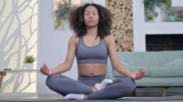 istock Young African Woman Meditating on Excercise Mat at home 1345619471