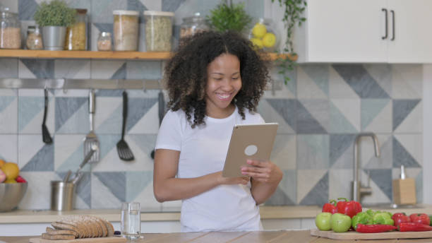 istock Young African Woman doing Video Call on Tablet in Kitchen 1345619484