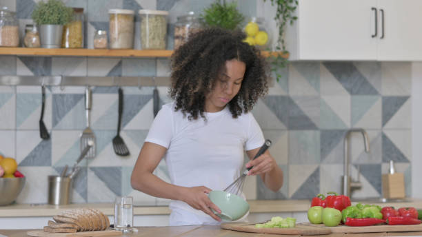 istock Young African Woman Cutting Vegetables in Kitchen 1345619522