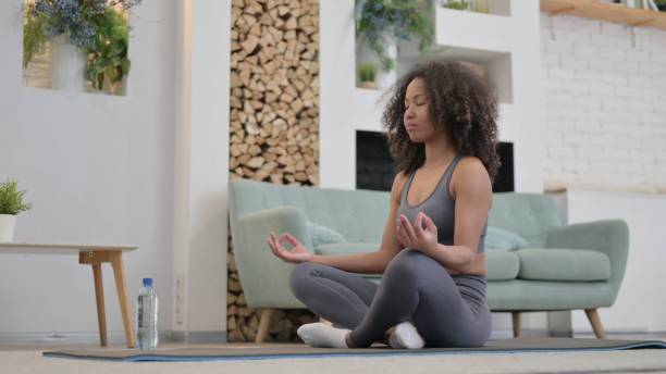 istock Peaceful Young African Woman Meditating on Excercise Mat at home 1345620439