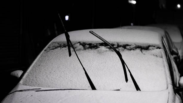 車のフロントガラスのワイパーは雪の中で凍結に対して立ち上がった。冬の条件の夜景。 - snow car window ice scraper ストックフォトと画像