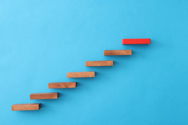 istock Red block standing over wooden on blue background closeup 1345622144