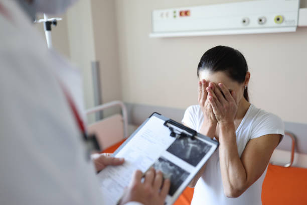 Doctor holding documents in front of crying patient in clinic Doctor holding documents in front of crying patient in clinic. Psychological support for people with cancer concept miscarriage stock pictures, royalty-free photos & images