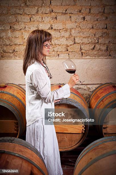 Mujer De Rojo De Degustación De Vino En Una Antigua Bodega Foto de stock y más banco de imágenes de Vino