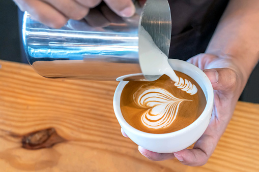 Imagen de primer plano de manos masculinas barista sirviendo leche hacer café latte arte en cafetería photo