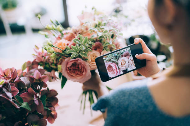 joven florista asiática, dueña de una floristería de una pequeña empresa, tomando fotos de un hermoso ramo. actualización y publicación en su tienda en línea y venta de productos en línea. dirigir un negocio en línea, comercio electrónico, compra - florist telephone flower business fotografías e imágenes de stock