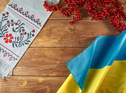 Bodegón ucraniano con elementos tradicionales: bandera de Ucrania, bordados nacionales y bayas de viburnum sobre un fondo de madera photo