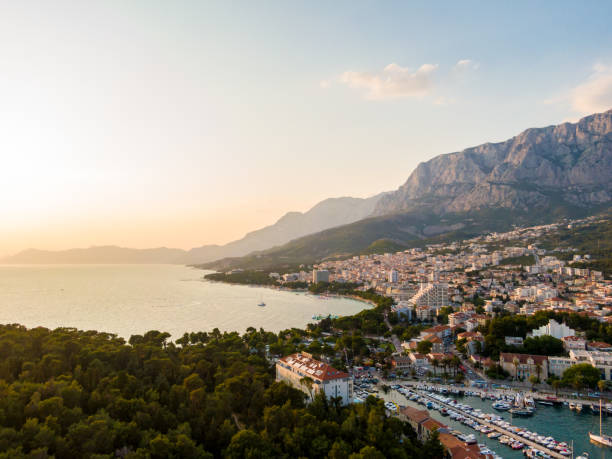 widok z lotu ptaka z drona na miasto makarska, chorwacja. zachód słońca nad miastem, plażą i se. góry biokovo w tle. czas letni. - makarska riviera zdjęcia i obrazy z banku zdjęć