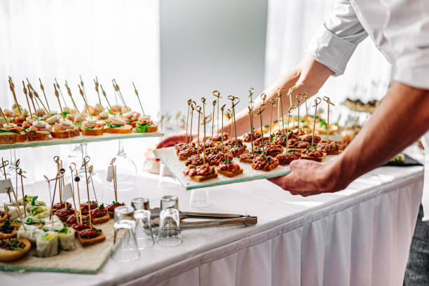 manos de un camarero preparan comida para una mesa buffet en un restaurante - appetizer fotografías e imágenes de stock