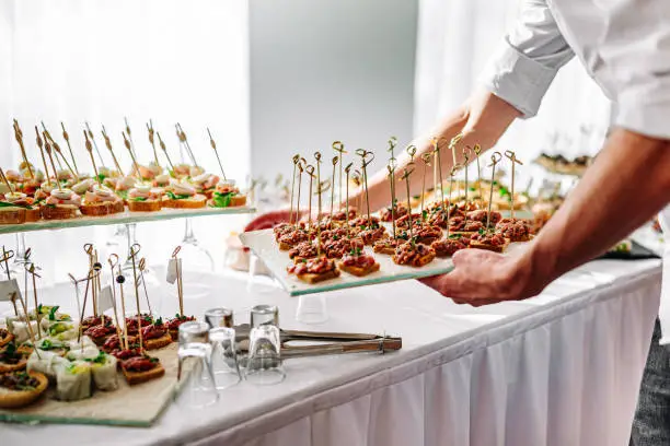 hands of a waiter prepare food for a buffet table in a restaurant