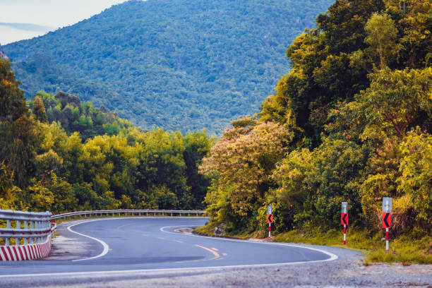 istock Time change future concept. Beauty panorama landscape Dry asphalt empty automobile winding road with marking lines in forested nebula mountain background evening, early autumn or late summer foliage 1345640204