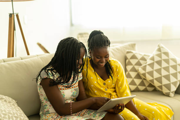 istock Two sisters sit next to each other to share some social media on an iPad 1345642362