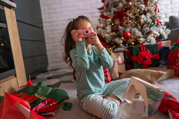 With her toy camera, she got for Christmas, excited girl imitating that she making a photography Happy and excited six year’s old girl, during Christmas morning opening her Christmas presents unwrapping stock pictures, royalty-free photos & images