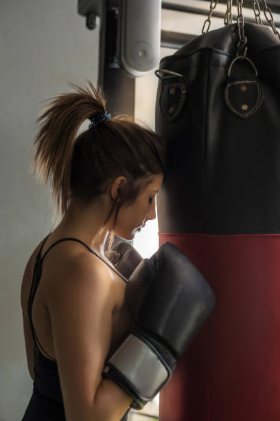 istock a girl is resting during a boxing training session. she is leaning on the training bag. 1345647657