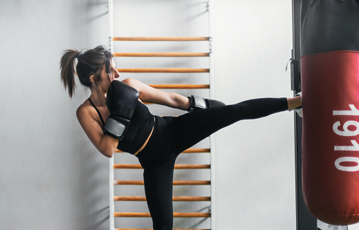 close-up of a girl training with a punching bag. she is kicking the bag.