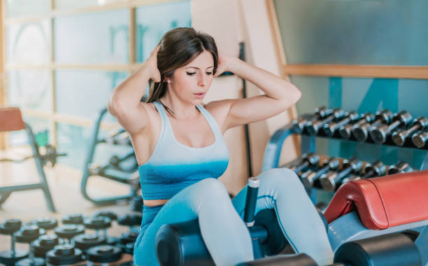 istock girl in gym practicing sit-ups on a bench. she has her hands on her head and is concentrating on her strength work. 1345647698