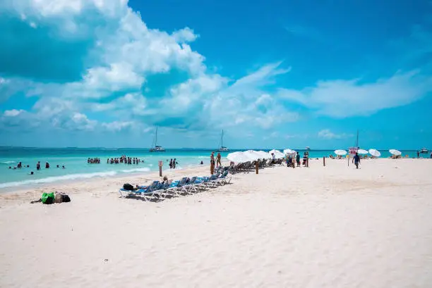 Cancun, Mexico. May 30, 2021. Deckchairs under canopy shade for resting on beach sand in front of sea with yachts. Tourists enjoying beach summer holiday