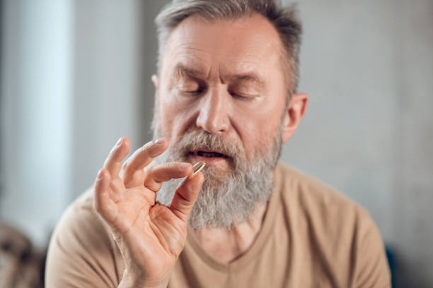 istock A bearded man holding a pill and looking at it 1345648822